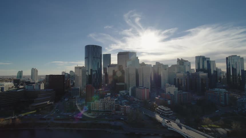 Tall buildings dominate a downtown area near the river against blue skies