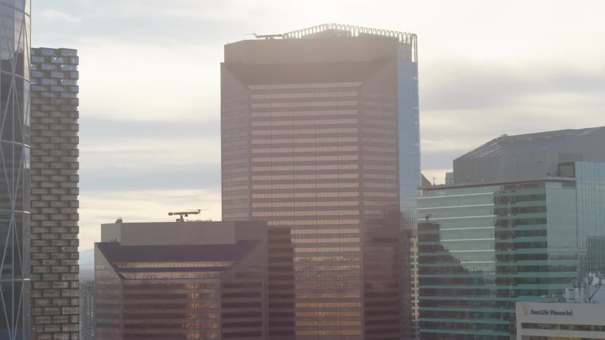The sun shines from behind a set of buildings in a downtown city