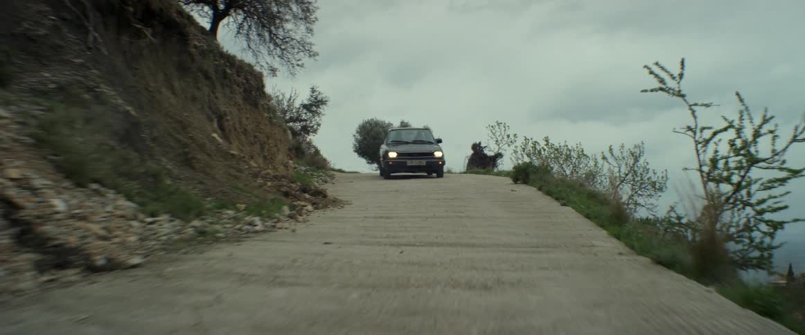 Car driving down a small road on a cloudy day