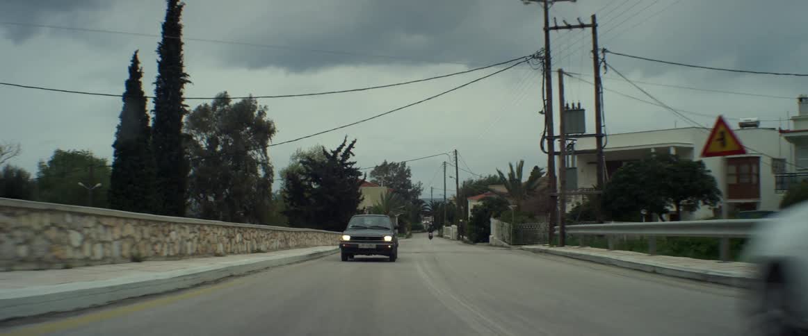 Black car driving down a road on a cloudy day