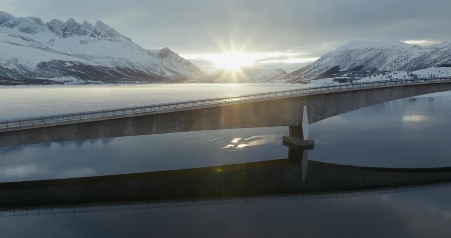 A bridge over a lake in the mountains at sunset