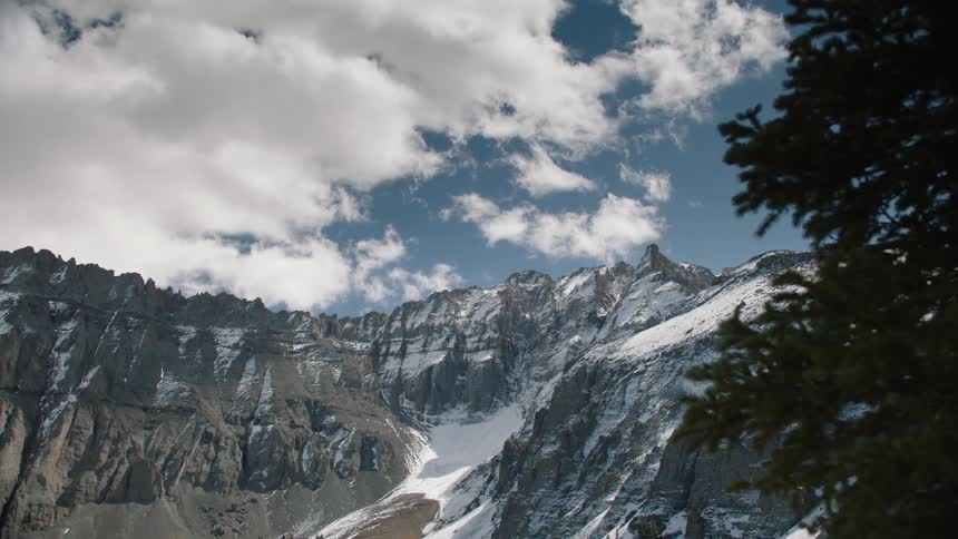 A snowcapped mountain peak under a blue sky with clouds