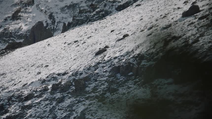 Snow covers mountains under a slightly cloudy sky
