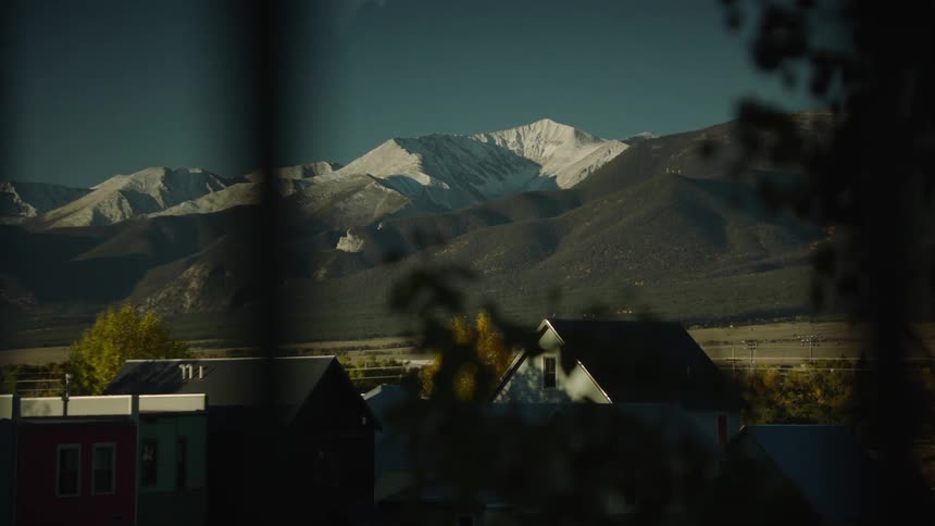 View from the window of a residential neighborhood with mountains in the background with snow on a blue sky day