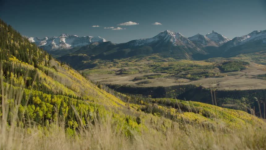 Landscape of hills and plateaus and surrounding mountain ranges with snow