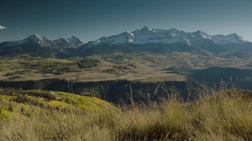 Mountains with vegetation and snowcovered peaks on the horizon against a blue sky