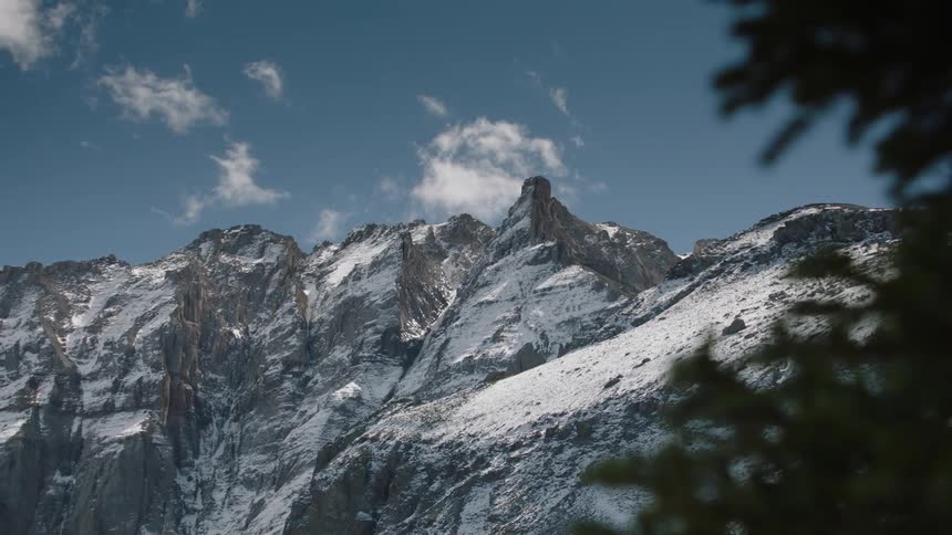 A snowcapped mountain peak under a blue sky with clouds