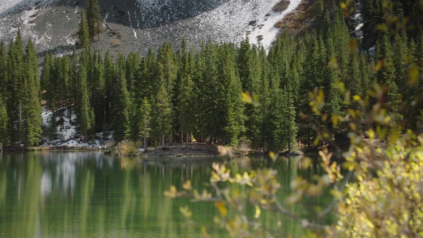 A calm lake surrounded by a mountainous forested setting