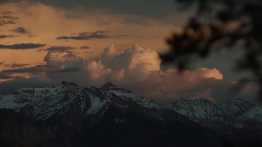 A mountain range at dusk with clouds in the sky