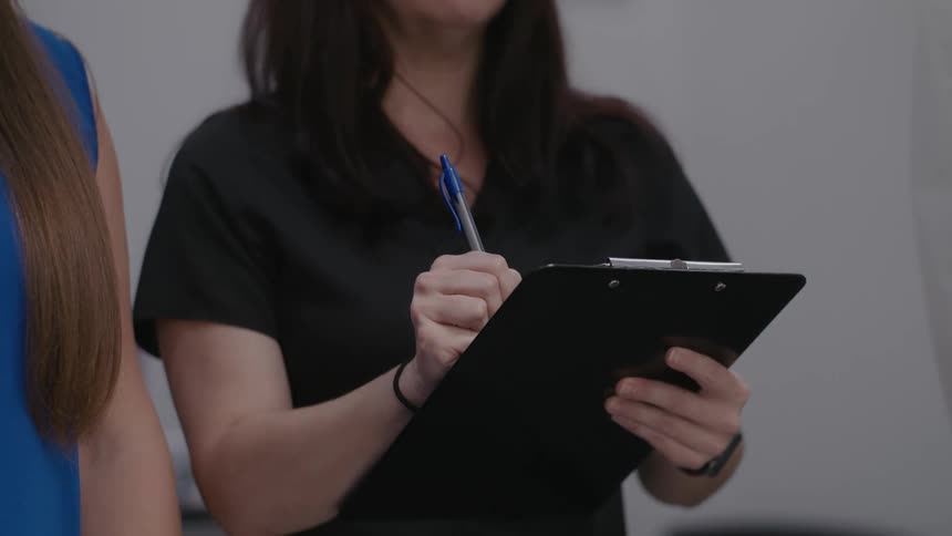Two women side by side with one of them taking notes on a clipboard