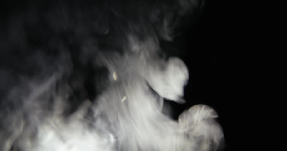 Black and white footage of flames and smoke rising in darkness