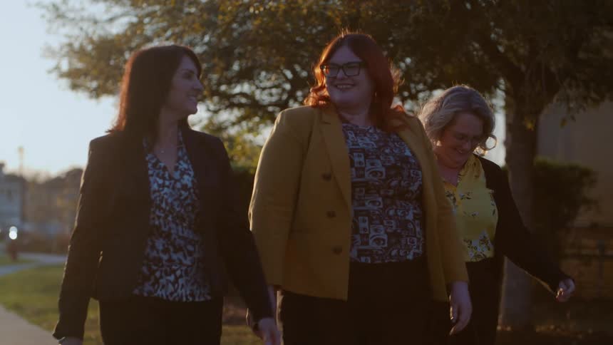Three friends walking while talking and smiling
