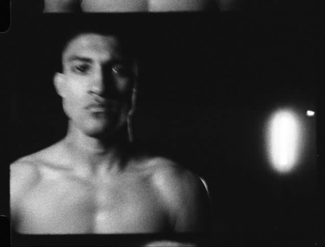 Portrait of shirtless man boxer indoors in dim lighting