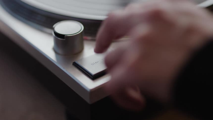 A closeup of a person pushing a button on a turntable