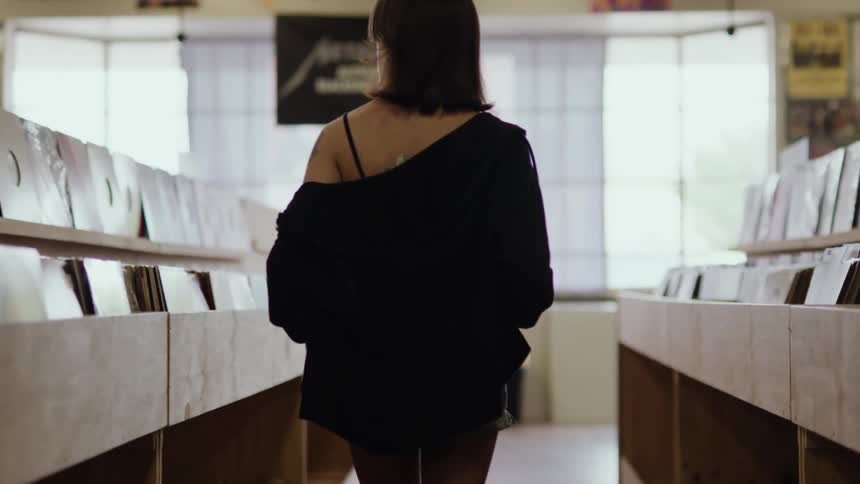 Woman from behind walking in an aisle of vinyl records