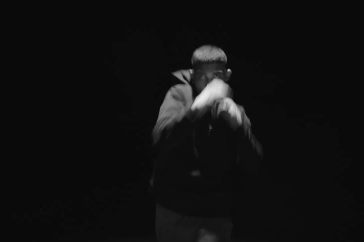 A boxer running and throwing punches under a spotlight at night