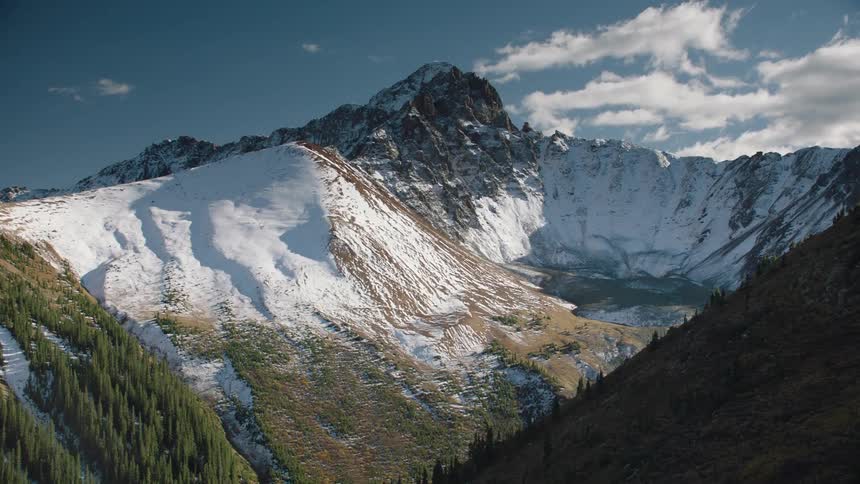 A snowcapped mountain peak under a blue sky with clouds