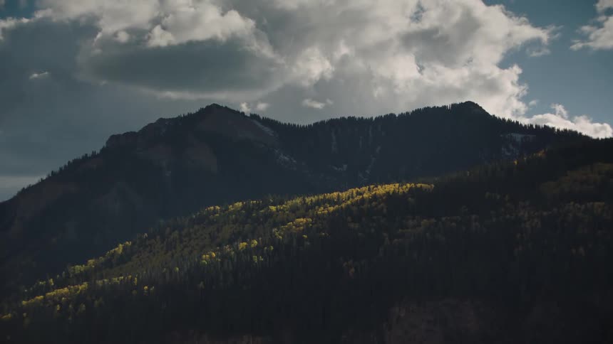 A mountain covered in dense forest under the clouds