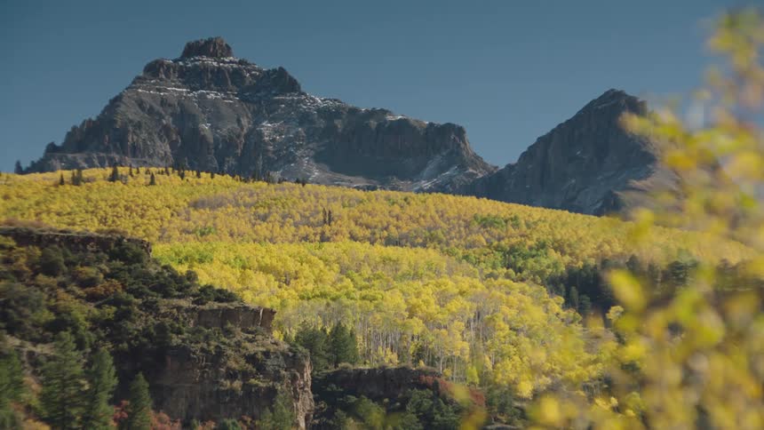 Landscape of hills covered with yellowish spring forests and mountainous peaks with cliffs