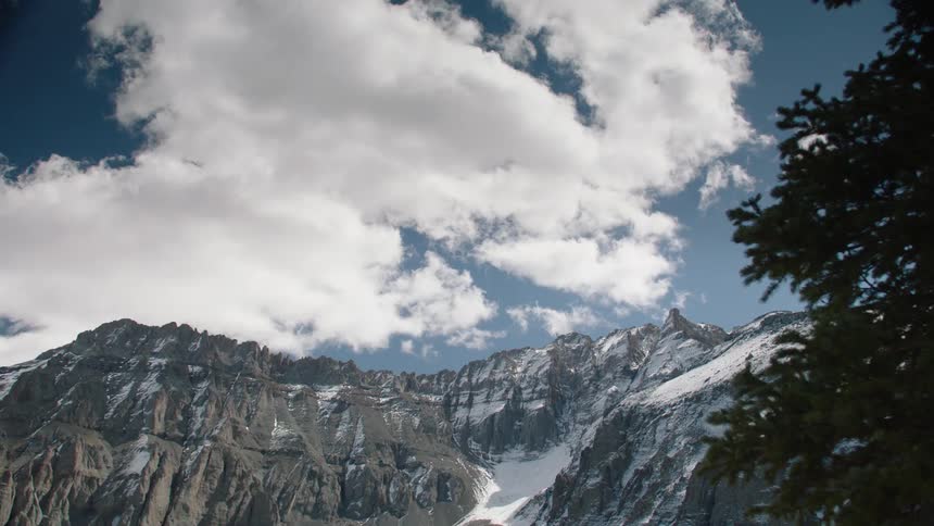 A snowcapped mountain peak under a blue sky with clouds