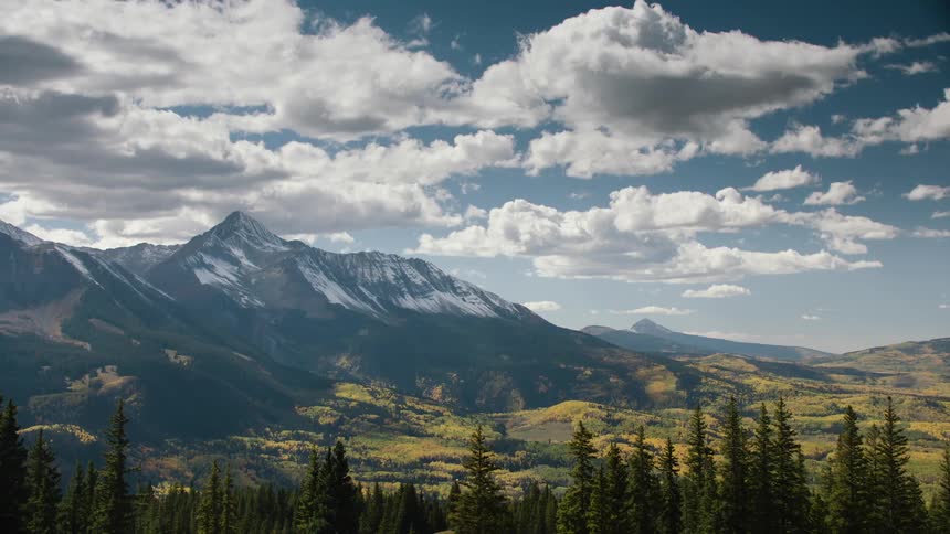 A mountain range with a prominent peak under a cloudy sky