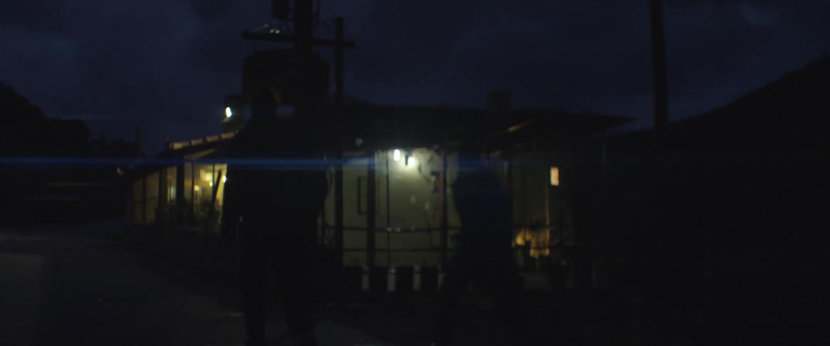 Two men walk out of their car and to a house at night