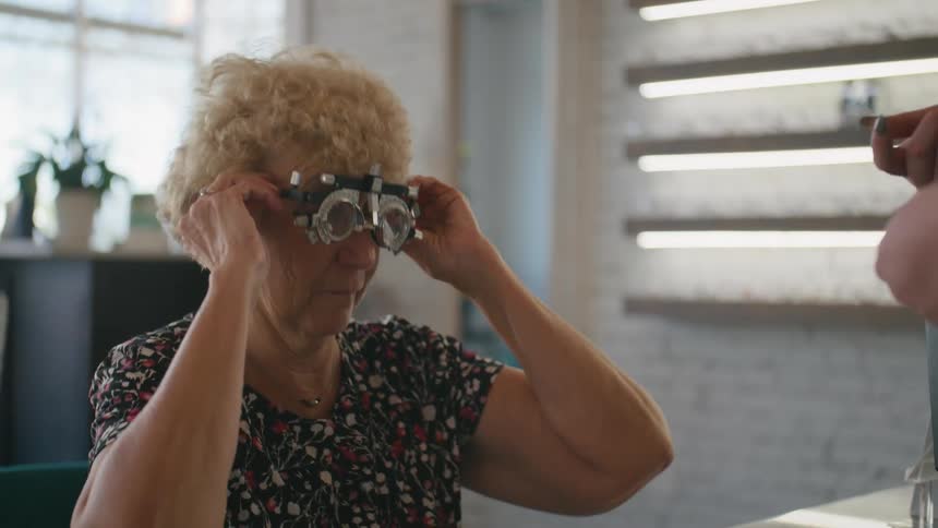 An optometrist places an eye examination tool on an elderly woman