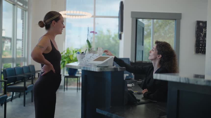 Receptionist at the counter talking to a woman in front of her