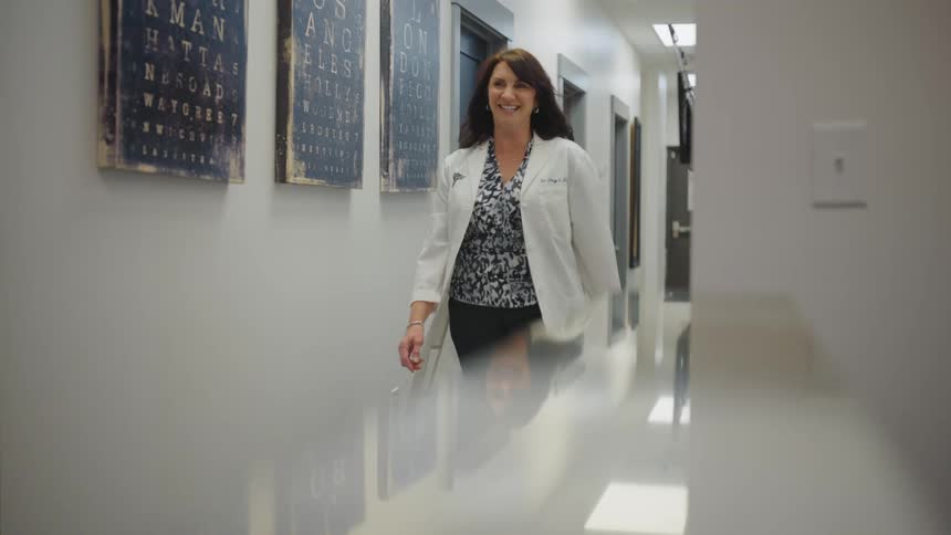 Female doctor smiles while walking down corridor