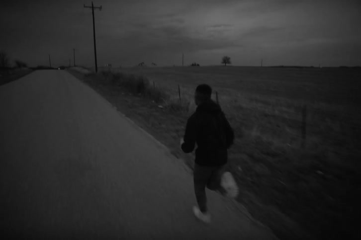Black and white footage of an individual jogging on a path