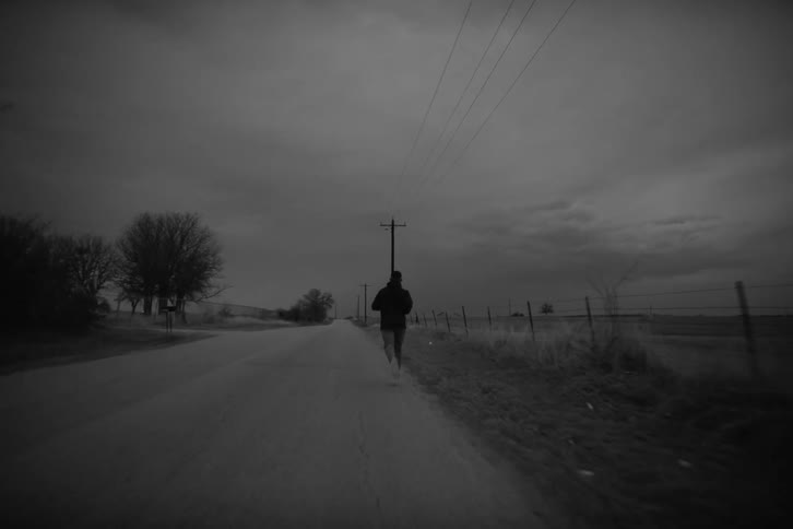 Man running on a road next to rural fields