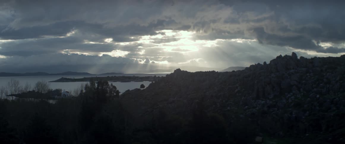 View of rocky hills, a lake and sun beams showing through clouds