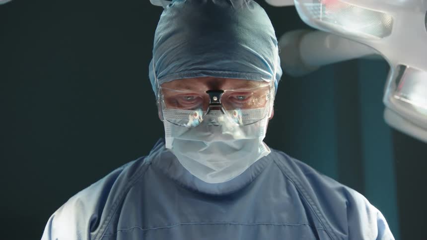Portrait of a male surgeon with glasses mask and protective clothing concentrated