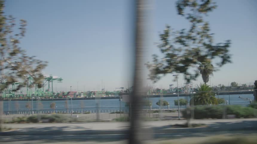 View from the window of a moving vehicle of the sea and a port