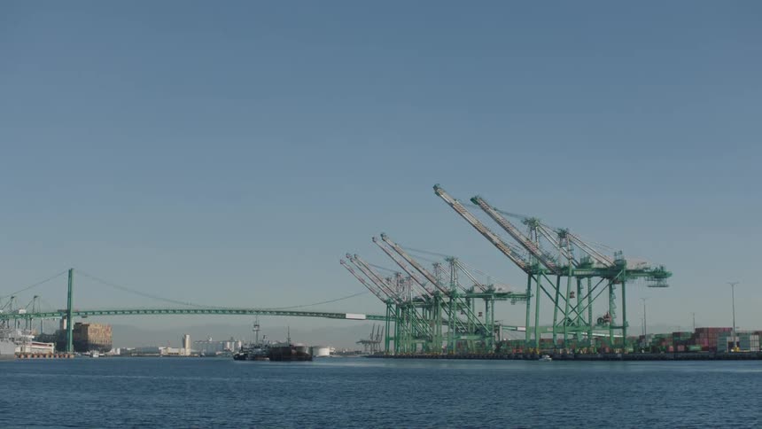 A shipping harbor on a river with multiple shipping containers and cranes