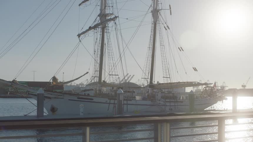 Sail boat moored at a dock with the morning sun reflection