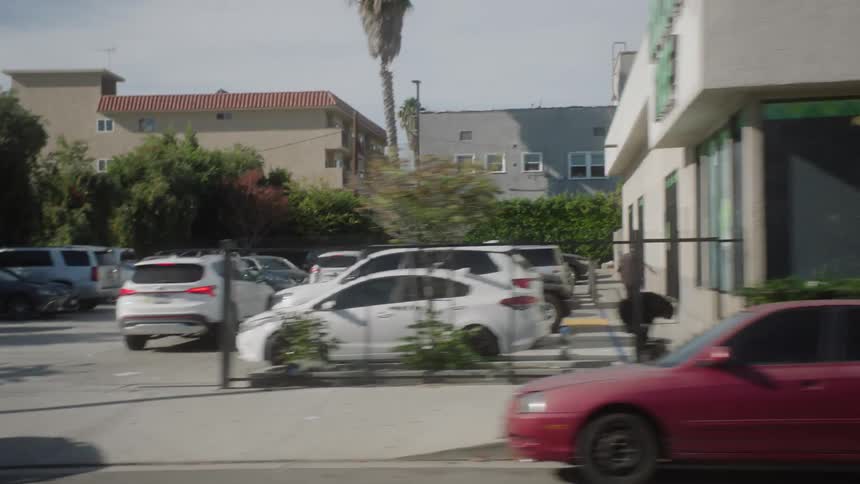 Cars parked and driving by businesses in a suburb