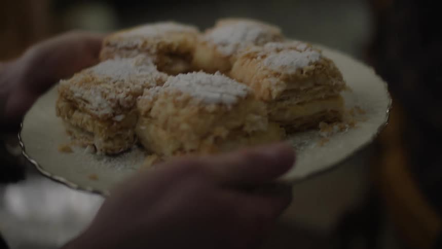 A man gives a plate of cake to an elderly man