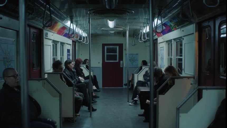Several people sitting on benches in a moving subway