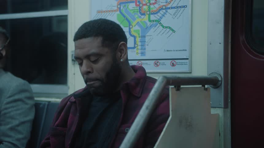 A black man explodes with laughter on a subway car