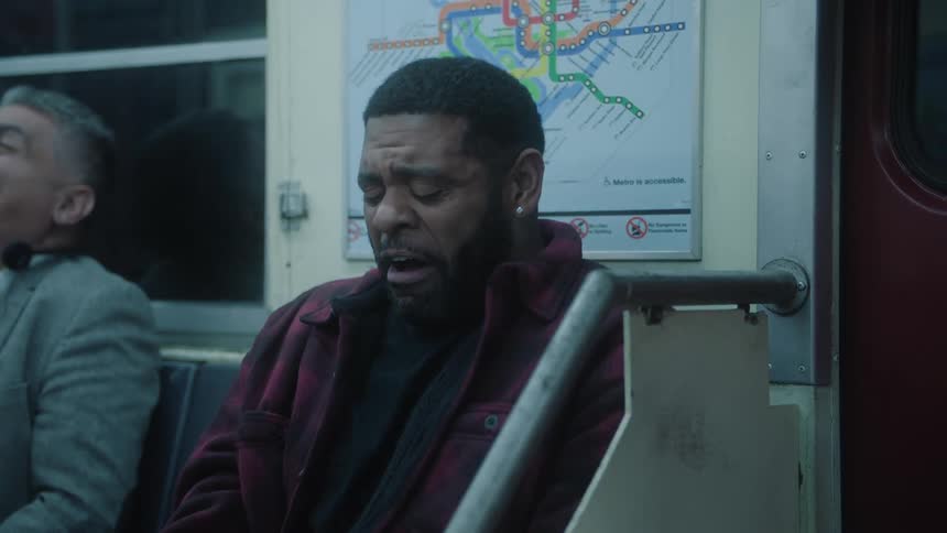 A man sitting on a subway train laughing
