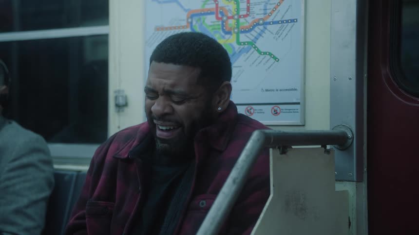 A man is sitting on a subway seat and he is laughing his off and behind him there is a map