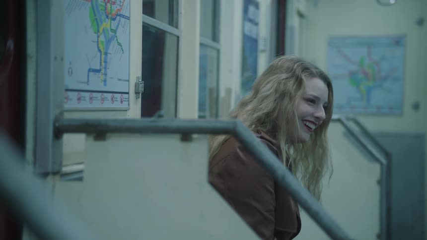 A blonde woman laughs while traveling in a subway