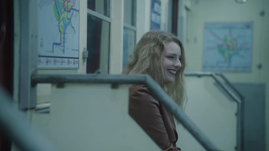 Blonde woman sitting on a bench in a moving train laughing