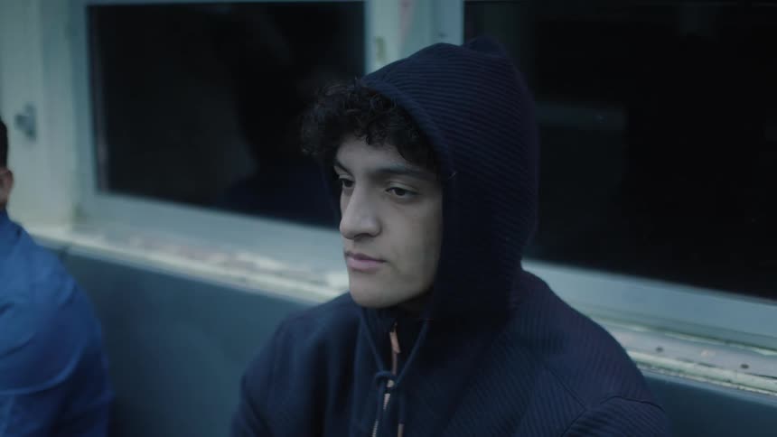 Man in a jacket and cap sitting on a train bench