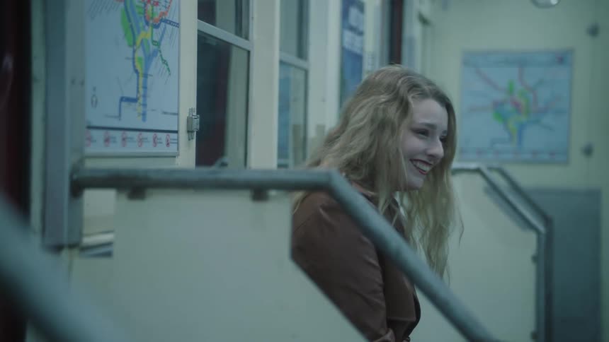 Young blonde woman sitting on the bench of a train smiling