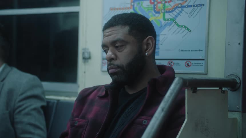 A man sitting at a subway looking pensive