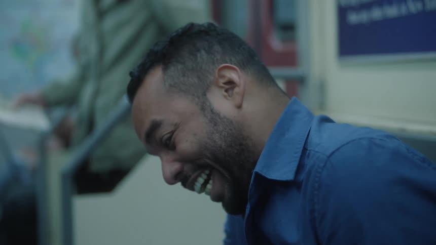 Man sitting on a train seat laughing
