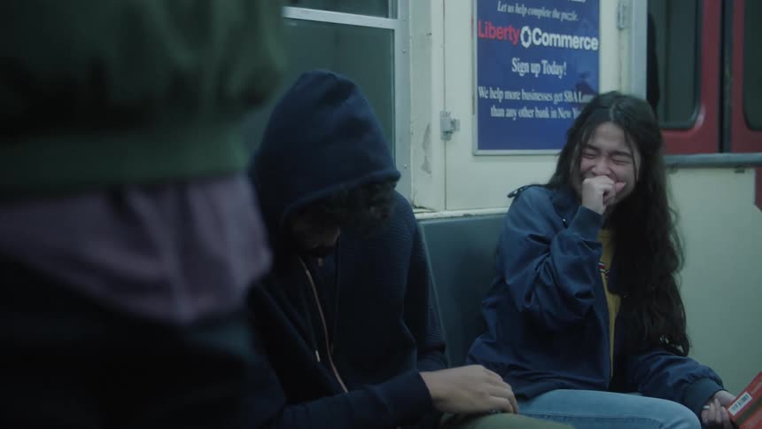 Two friends sitting on a suwbay train laughing