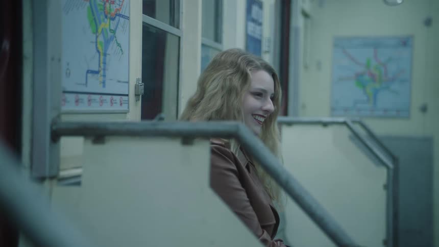 A woman is laughing while riding the subway